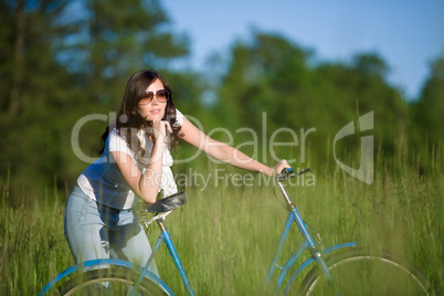 Woman with old-fashioned bike in summer meadow