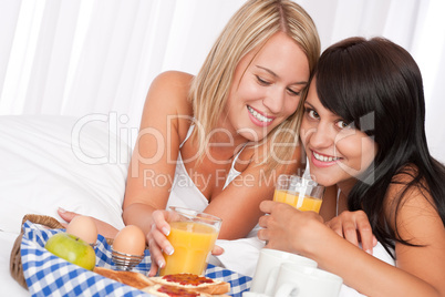 Two girlfrinds having breakfast in white bed