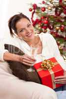 Smiling woman with Christmas present and glass of champagne
