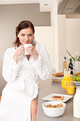 Young woman enjoying coffee and breakfast in kitchen