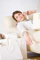 Young businesswoman with shopping bag on sofa