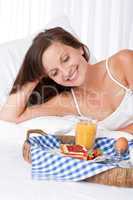 Happy woman in white bed having breakfast