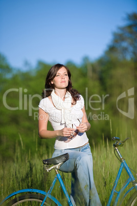 Woman with old-fashioned bike in summer meadow