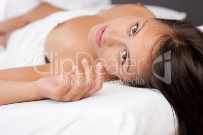 Young brown hair woman lying in white bed
