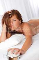 White lounge - Tired woman holding silver alarm clock