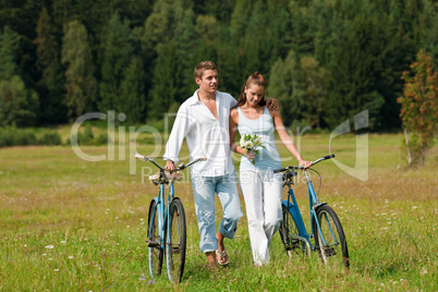 Romantic young couple walking with old bike