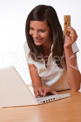 Happy teenager with laptop holding protein bar