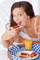 Happy woman eating toast for breakfast