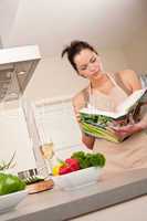 Young woman reading cookbook in the kitchen