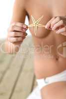 Naked woman with starfish on beach