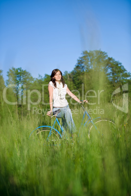 Woman with old-fashioned bike in summer meadow