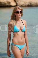 Blond fashion model sunbathing in bikini on beach