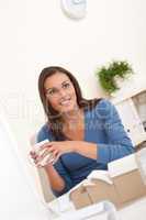 Brown hair female architect sitting at office holding coffee