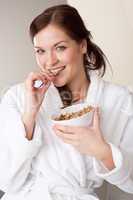 Woman in bathrobe holding bowl with cereals for breakfast