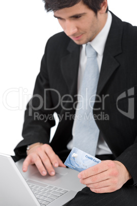 Young businessman with laptop holding credit card