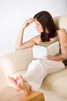 Young woman read book relaxing on sofa