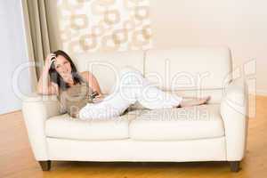 Woman holding music player listening on sofa home