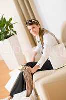 Young businesswoman with shopping bag on sofa