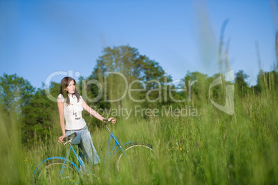 Woman with old-fashioned bike in summer meadow