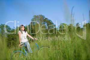 Woman with old-fashioned bike in summer meadow