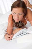 White lounge - Young woman writing notes and lying on bed