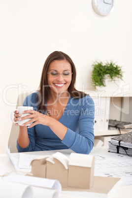 Brown hair female architect sitting at office holding coffee