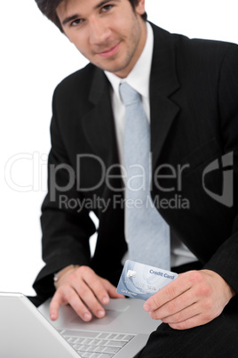 Young businessman with laptop holding credit card