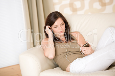 Woman holding music player listening on sofa home