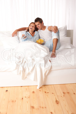 Young man and woman lying down in white bed