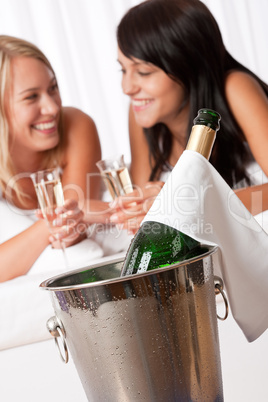 Two smiling women drinking champagne in luxury hotel room