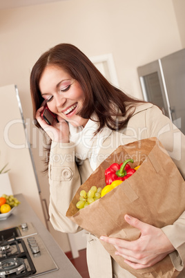 Smiling woman with mobile phone holding shopping bag