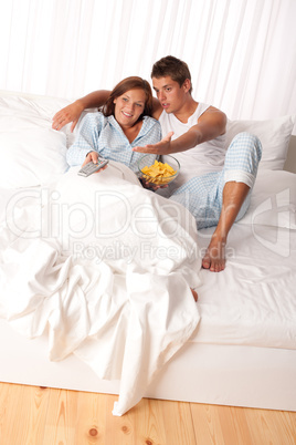 Young man and woman lying down in white bed