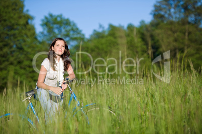 Woman with old-fashioned bike in summer meadow