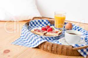 Homemade breakfast on wicker tray with checked teacloth