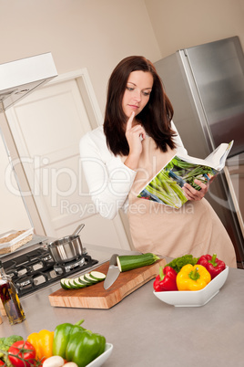 Young woman reading cookbook in the kitchen