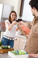 Young couple toasting with red wine in kitchen