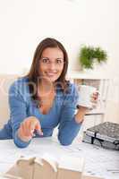 Brown hair female architect sitting at office holding coffee