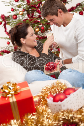 Young couple with champagne in front of Christmas tree
