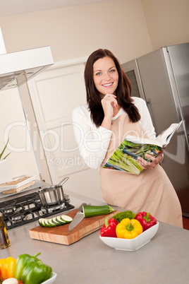 Smiling woman holding cookbook in the kitchen