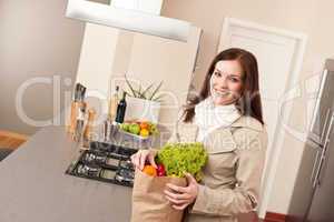 Woman holding shopping bag with grocery in kitchen