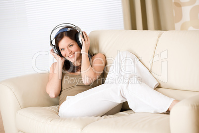 Happy woman with headphones on sofa in lounge