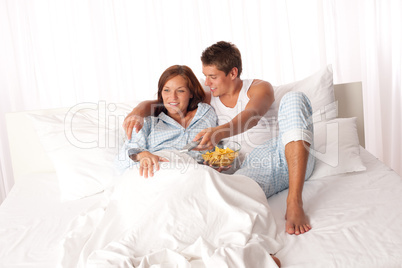 Young man and woman lying down in white bed