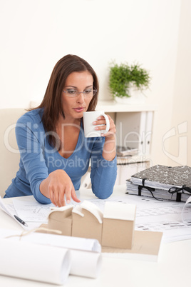 Young female architect holding cup of coffee