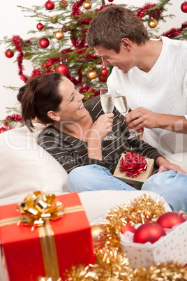 Young couple with champagne in front of Christmas tree
