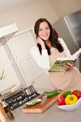 Smiling woman holding cookbook  in the kitchen