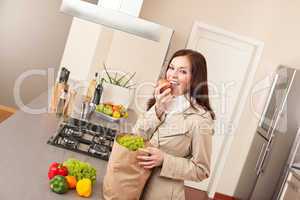 Young woman unpacking shopping bag in kitchen