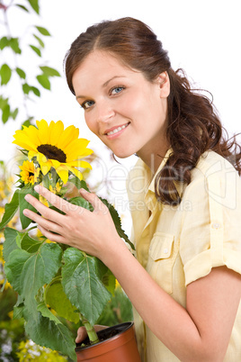 Smiling woman holding flower pot with sunflower