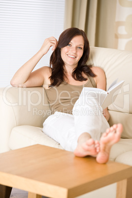 Young happy woman read book on sofa