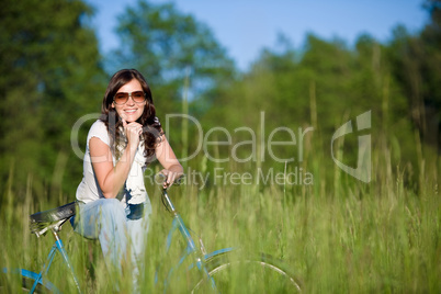 Woman with old-fashioned bike in summer meadow