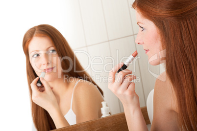 Body care series - Beautiful red hair woman applying lipstick